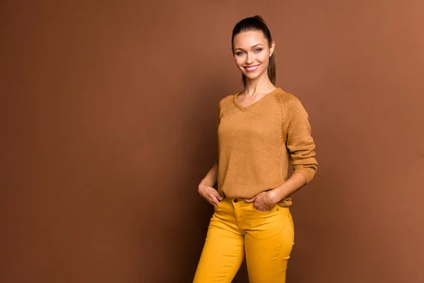 Foto de chica dulce agradable alegre confiada de pie con sus manos en bolsillos sonriendo radiante aislado sobre fondo de color pastel marrón — Foto de Stock