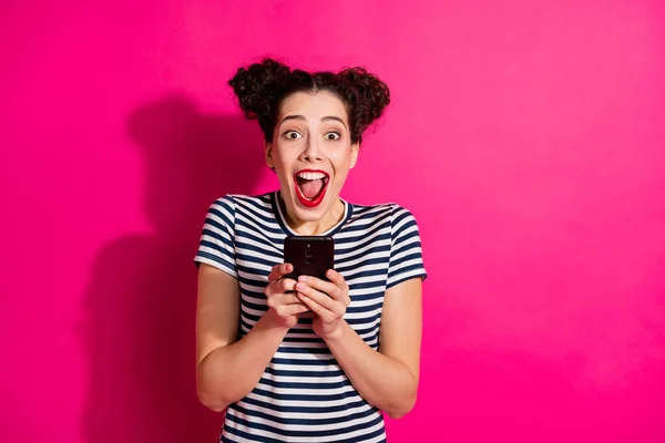 Photo of cheerful cute trendy nice charming fascinating attractive youngster screaming while watching video on phone wearing striped t-shirt isolated over fuchsia vivid color background