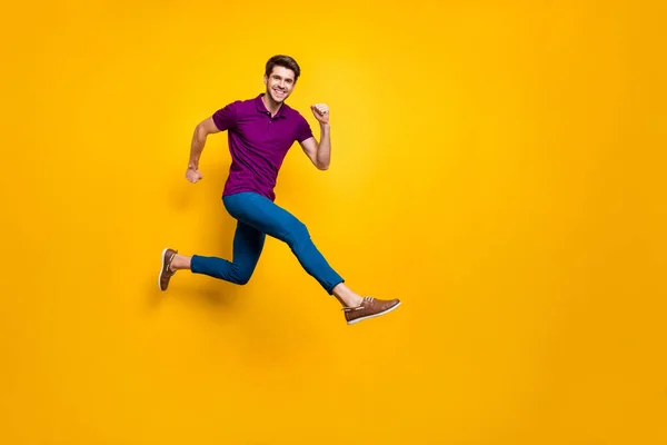 Comprimento total do corpo tamanho phoo de cabelos castanhos alegre atraente homem vestindo calças azuis calças roxo t-shirt calçado aspirante saltar correndo isolado sobre amarelo cor viva fundo — Fotografia de Stock