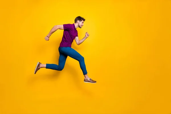 Full length body size side profile foto van een snelle knappe man in een blauwe broek broek schoeisel springen naar lege ruimte geïsoleerd over levendige kleur achtergrond — Stockfoto