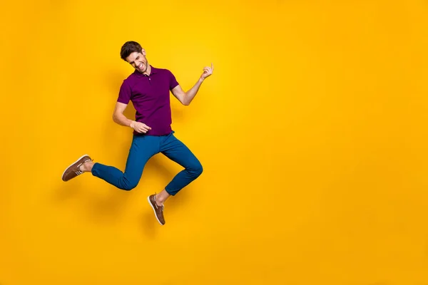 Foto de alegre louco extasiado homem feliz fingindo estar tocando guitarra imaginária usando calças azuis calças sapatos isolados sobre amarelo fundo de cor vívida — Fotografia de Stock