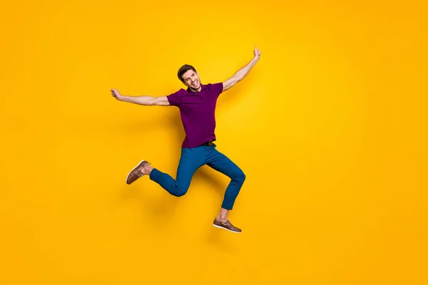 Full length body size photo of cheerful ecstatic free man wearing blue pants trousers aspiring jumping towards future isolated over yellow vivid color background — стоковое фото