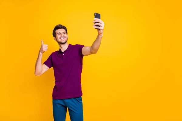 Çekici, neşeli, esmer adamın portresi. Selfie çekiyor. Parlak, parlak, parlak, parlak, sarı arka planda izole edilmiş başparmağını gösteriyor. — Stok fotoğraf
