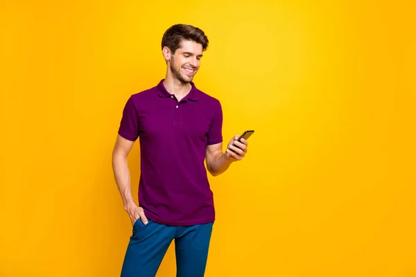 Portret van zijn hij mooie aantrekkelijke inhoud vrolijke vrolijke blij man dragen violette shirt met behulp van gadget delen repost smm als geïsoleerd op heldere levendige glans levendige gele kleur achtergrond — Stockfoto