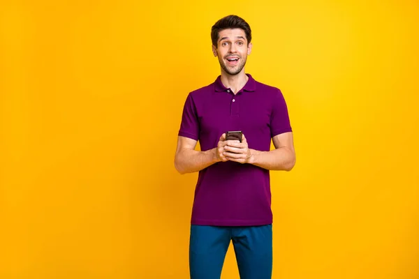 彼の素敵な魅力的な中毒者の肖像画明るい鮮やかな輝き鮮やかな黄色の色の背景に隔離されたデジタルデバイスの近代的な技術を使用して紫のシャツを着て陽気な陽気な陽気な陽気な陽気な陽気な男 — ストック写真