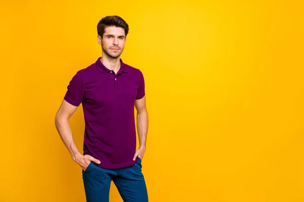 Portrait de son il beau contenu attrayant gars sérieux portant chemise violette tenant la main dans des poches isolées sur brillant vif fond de couleur jaune vif — Photo