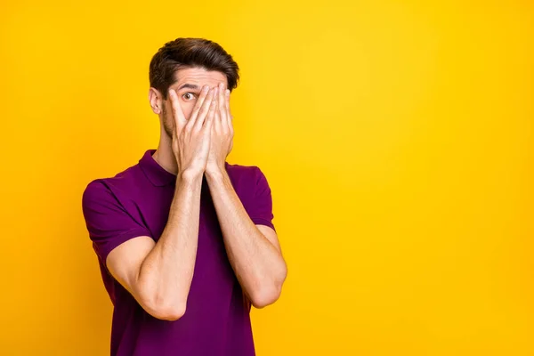 Ritratto del suo bel ragazzo attraente spaventato che indossa camicia viola nascondendo il viso nelle palme sbirciando isolato su luminoso vivido brillare vibrante sfondo di colore giallo — Foto Stock