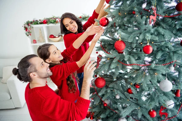 Porträtt av tre trevliga attraktiva vackra söta charmiga glada glada glada försiktig familj tillbringar vintern christmastime fritid dekorera gran evergreen i modern ljus vit interiör vardagsrum — Stockfoto