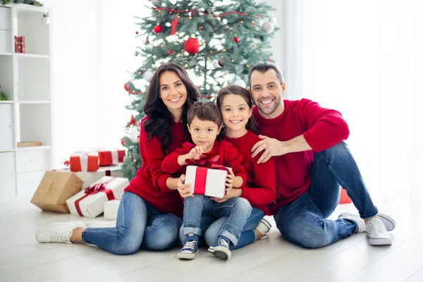 Helkroppsfoto av stor full charmig pappa mamma skolflicka liten pojke hålla paket för jul kväll njuta av jul med brunett hår bär röd pullover jeans jeans i huset inomhus — Stockfoto