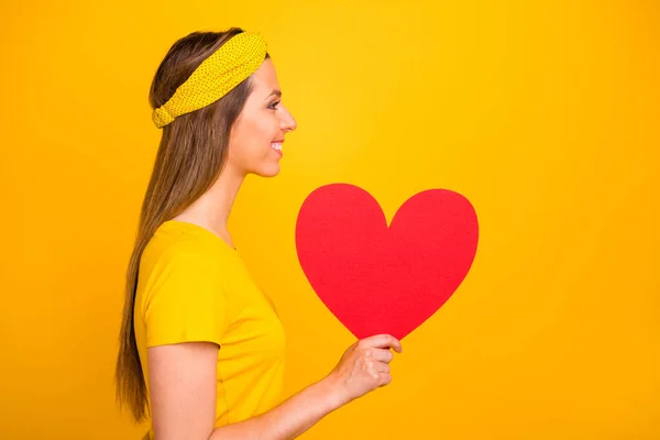 Adatlap side photo of candid millennial holding big heart for valentine day looking with beaming smile isolated over yellow background — Stock Fotó