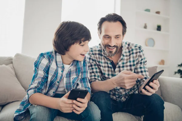 Sms messaggio tecnologia moderna concetto di generazione del mondo digitale. Foto di maturo ragazzo barbuto eccitato mostrando nuovo sito di social page negozio con giocattoli elettronici al suo figlio più giovane seduto sul divano — Foto Stock