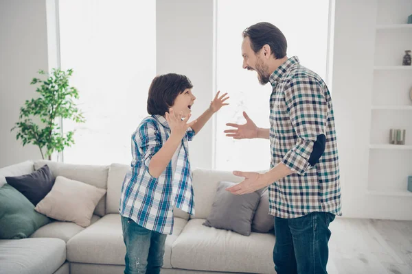 Perfil lado ver retrato de dos bonitos enojado cabreado chicos papá y pre-adolescente hijo en casual comprobado camisa teniendo gran pelea desacuerdo comportamiento en blanco claro moderno estilo interior sala de estar — Foto de Stock