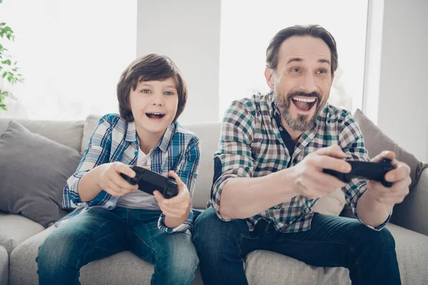 Portrait of two nice attractive cheerful cheery glad guys dad and pre-teen son spending day playing online video game at light white modern style interior house living-room indoors — Stock Photo, Image