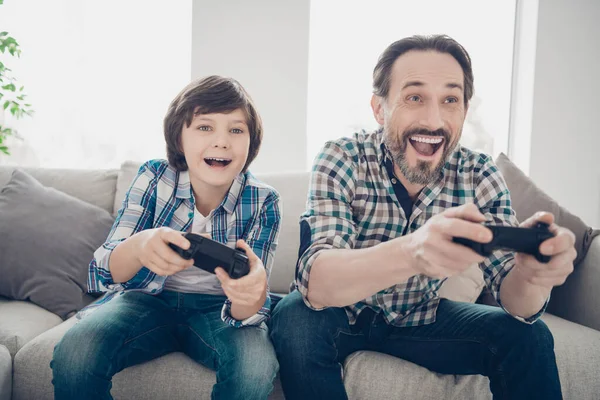 Retrato de dois agradáveis atraentes alegres alegres rapazes felizes pai e pré-adolescente filho passar o dia jogando videogame on-line no estilo moderno branco claro casa interior sala de estar dentro de casa — Fotografia de Stock