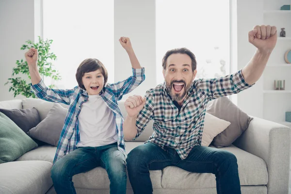 爸爸和儿子在电视上看体育节目，在室内浅白的现代风格的室内客厅里玩得很开心。 — 图库照片