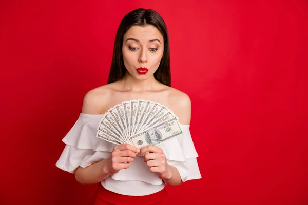 Portrait de la personne mignonne étonnée tenant l'argent regarder porter des épaules isolées sur fond rouge — Photo