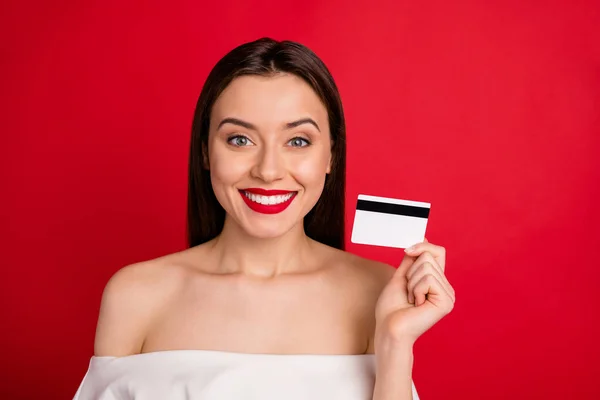 Foto de cerca de la atractiva dama con sonrisa dentada que sostiene la tarjeta de crédito aislada sobre el fondo rojo — Foto de Stock