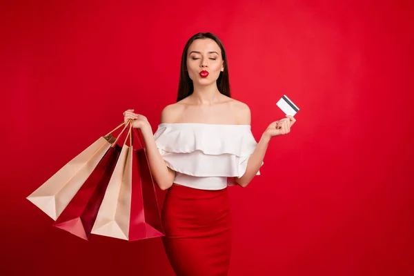 Retrato de encantador doce pessoa segurando sacos cartão de crédito fechar os olhos enviar beijos de ar isolado sobre fundo vermelho — Fotografia de Stock