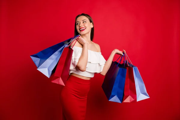 Portret van mooie prachtige millennial houden heldere zakken kijken dragen top geïsoleerd over rode achtergrond — Stockfoto
