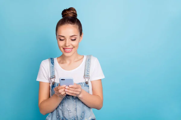 Retrato de senhora encantadora segurando tecnologia moderna olhando para a tela vestindo branco t-shirt jeans jeans macacão isolado sobre fundo azul — Fotografia de Stock