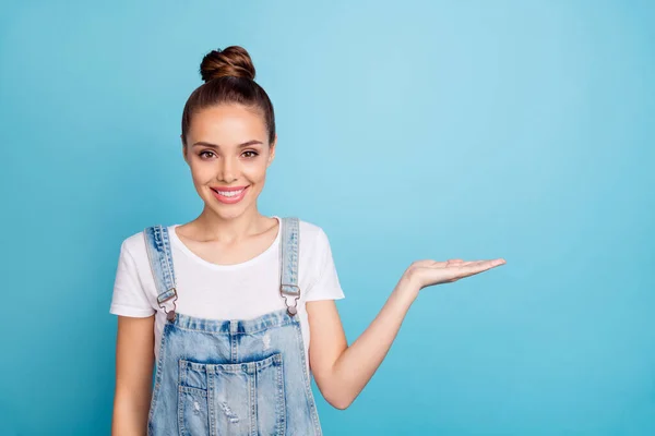 Porträtt av härlig promotor håller hennes hand ler bär vit t-shirt denim jeans overaller isolerad över blå bakgrund — Stockfoto