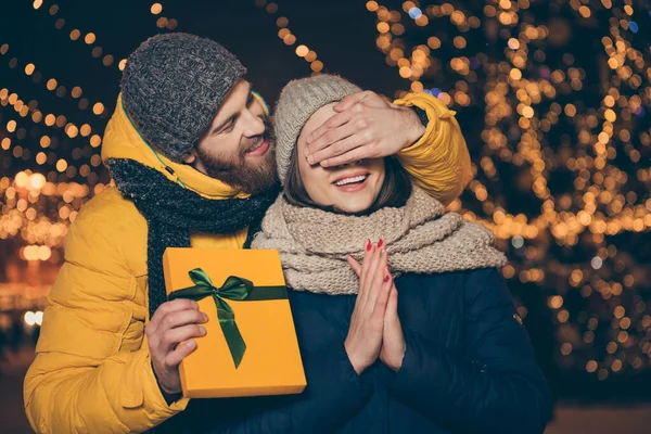 Bil bakalım kim. İki kişinin fotoğrafı, gözlerini kapatan bir çift, sürpriz bir şekilde Noel hediyesi kutusunu tutuyor. Ceket giyiyor, eşarp takıyor, yeni yıl ruhlar parkına gidiyor. — Stok fotoğraf