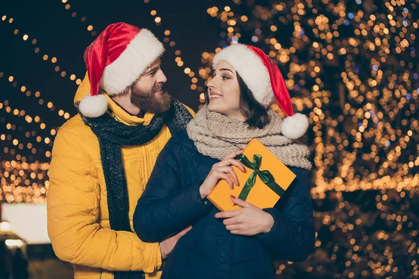 İki kişinin fotoğrafı. Çift erkek. Heyecanlı kadın, elinde Noel Baba şapkası takıyor. Yeni yıl ruhlar parkında Noel Baba şapkası takıyor. — Stok fotoğraf