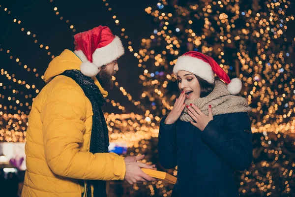 Я твоя приватна дитина Санта. Фото хлопця, який дарує збуджену здивовану леді свою різдвяну подарункову коробку новорічну традицію носити пальто Санта-шапки шарфи неолінійний парк на відкритому повітрі — стокове фото