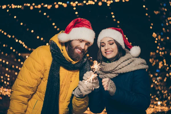 Baixo ângulo vista foto do casal cara senhora duas pessoas no x-mas celebração parque segurar sparklers ao ar livre newyear festa usar casacos quentes santa tampas lenços luvas fora — Fotografia de Stock