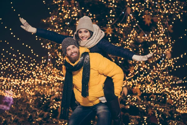 Фото двох людей хлопець леді ходить вогнями нічний парк новорічний вечір, тримаючи стерво, вдаючи крила польоту літак носити зимові пальто шарфи капелюхи на відкритому повітрі — стокове фото