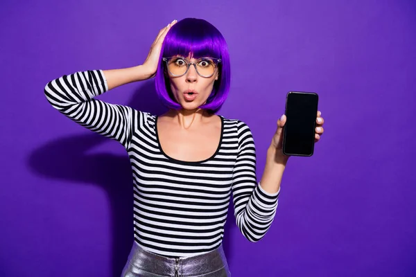 Portrait of puzzled millennial touch head with hand holding modern technology isolated over violet purple background — Stock Photo, Image