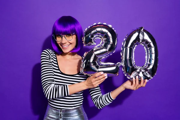 Foto von erstaunlichen Dame halten Hände Ballons feiern 20 Jahre Party tragen Spezifikationen gestreiften Pullover isoliert lila Hintergrund — Stockfoto