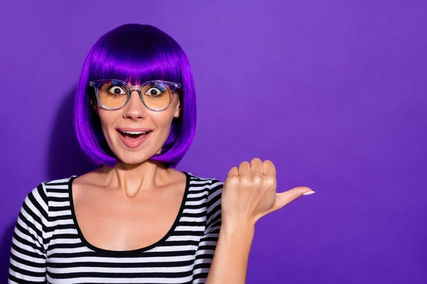 Foto de señora loca que indica el espacio vacío del dedo con la boca abierta desgaste peluca a rayas pulóver aislado fondo púrpura — Foto de Stock