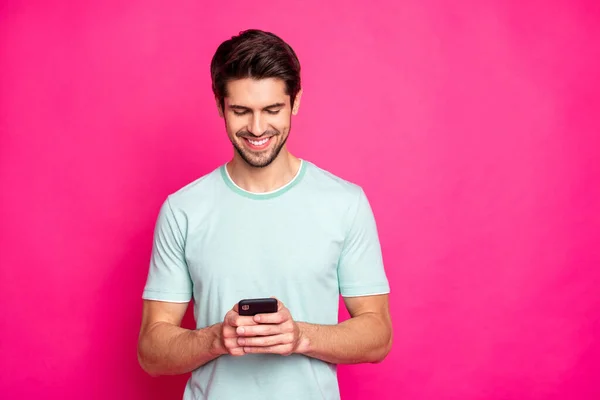Foto do cara blogueiro segurando telefone em mãos verificando assinantes toothy sorrindo desgaste roupa casual isolado vívido cor-de-rosa fundo — Fotografia de Stock