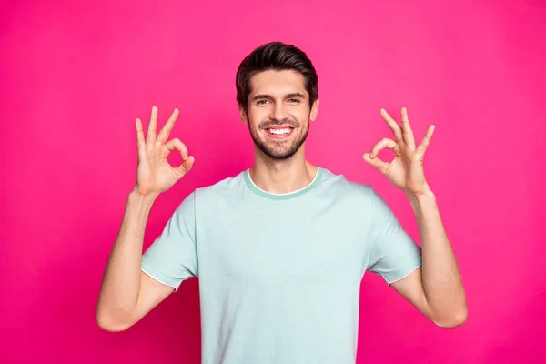 Foto de macho divertido mostrando símbolo okey expresando acuerdo y actitud positiva desgaste casual camiseta aislado vibrante color rosa fondo — Foto de Stock
