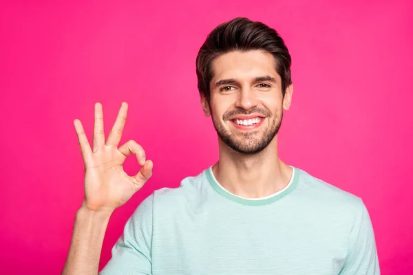 Foto av fantastiska macho kille visar okey symbol uttrycker samtycke och positiv attityd bära casual t-shirt isolerad levande rosa färg bakgrund — Stockfoto