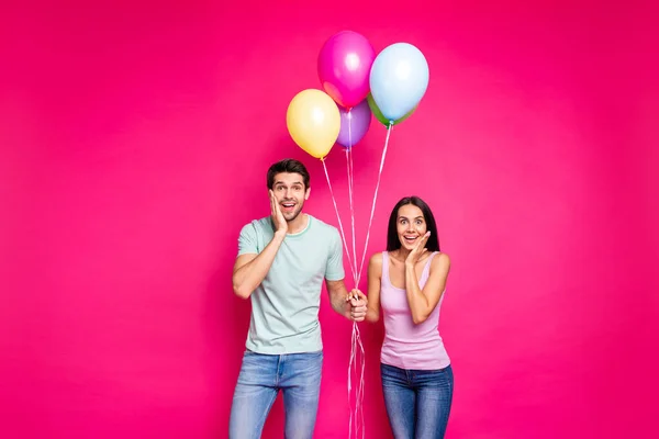 Photo of funny guy and lady holding air balloons arms on cheeks not believe unexpected surprise from friends wear casual outfit isolated pink color background — Stock Photo, Image