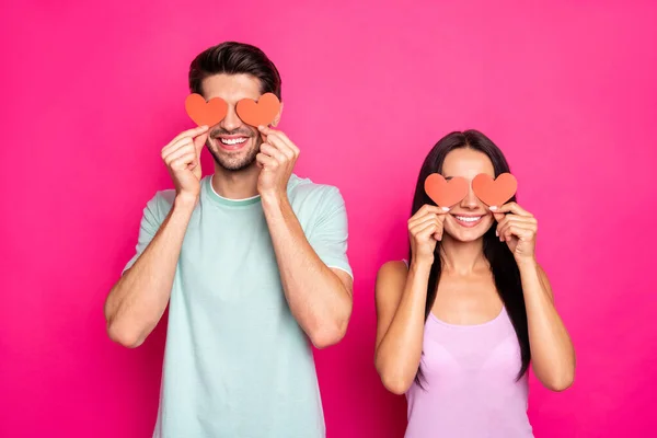 Foto van een geweldige man en dame met kleine papieren hartjes in de handen verbergen ogen nodigen elkaar uit om student prom dragen casual outfit geïsoleerde roze kleur achtergrond — Stockfoto