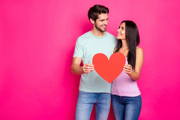 Foto de un chico increíble y una dama abrazándose sosteniendo un gran corazón de papel en las manos expresando los mejores sentimientos use un traje casual aislado de color rosa de fondo — Foto de Stock