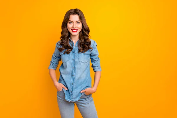 Foto de alegre bonito agradável encantador linda menina sorrindo toothily de mãos dadas em bolsos isolados sobre fundo de cor vívida amarela — Fotografia de Stock