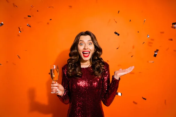Retrato de sorprendida chica funky celebrar vidrio con champán impresionado por confeti volando cayendo en celebración de x-mas llevar ropa de color burdeos con clase aislado sobre fondo de color naranja —  Fotos de Stock