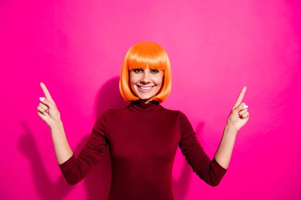 Foto de señora divertida en peluca brillante publicidad nuevos precios mostrados en la cartelera desgaste cuello alto rojo aislado color rosa fondo —  Fotos de Stock