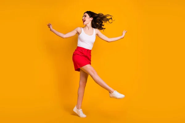楽しい女性のフルサイズプロフィール写真手を上げる脚喜び夏の週末暖かい風吹いて摩耗白いタンクトップ赤いスカートの靴孤立黄色明るい色の背景 — ストック写真