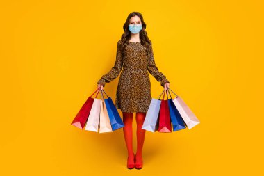 Full length body size view of her she nice attractive rich wealthy wavy-haired lady carrying new clothes garment wearing mask quarantine isolated bright vivid shine vibrant yellow color background clipart