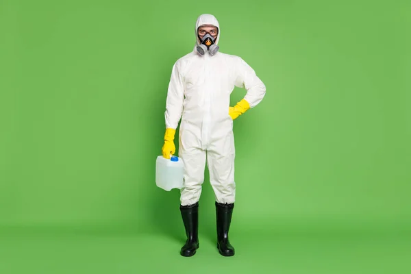 Full length body size view of his he disinfectant wearing gas mask holding in hand big bottle sanitizer sars ncov covid19 cov ebola influenza prevention isolated over green pastel color background