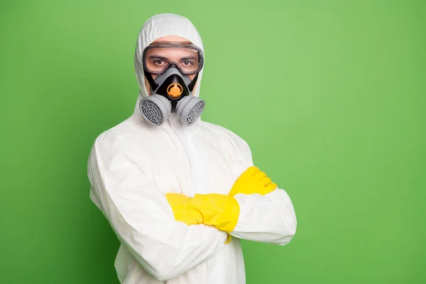 Close-up portrait of his he nice content serious professional disinfectant wearing gas mask anti viral pollution radiation quarantine folded arms isolated over green pastel color background