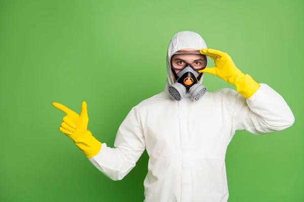 Retrato de su agradable desinfectante profesional seguro de usar tocando la máscara de gas de fijación que muestra espacio de copia restricciones de cuarentena noticias aisladas sobre fondo de color pastel verde —  Fotos de Stock