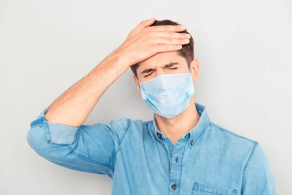 青いシャツの病気の若い男の肖像は、彼の頭に触れる、医療安全面マスクを着用痛みインフルエンザ呼吸器疾患症状温度、コロナウイルスパンデミック2020の概念 — ストック写真