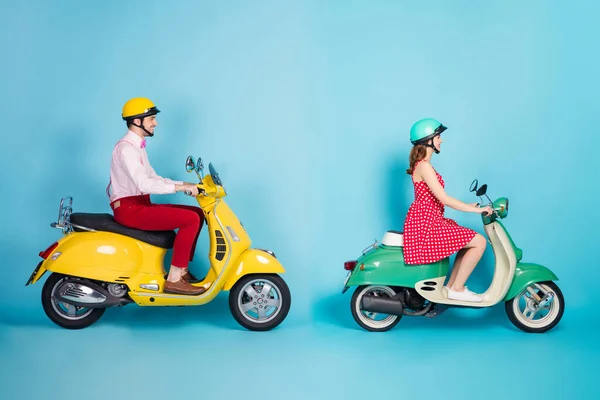 Full size profiel foto van grappige dame guy paar rijden retro bromfiets reizigers gemakkelijke manier verkeer jam goed humeur niet haasten vintage outfit beschermende caps geïsoleerde blauwe kleur achtergrond — Stockfoto