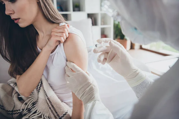 Photo of young sick ill patient lady sit sofa unwell call emergency doc virologist flu cold covid injection hand shoulder medication help wear latex gloves protective uniform indoors — Stock Photo, Image